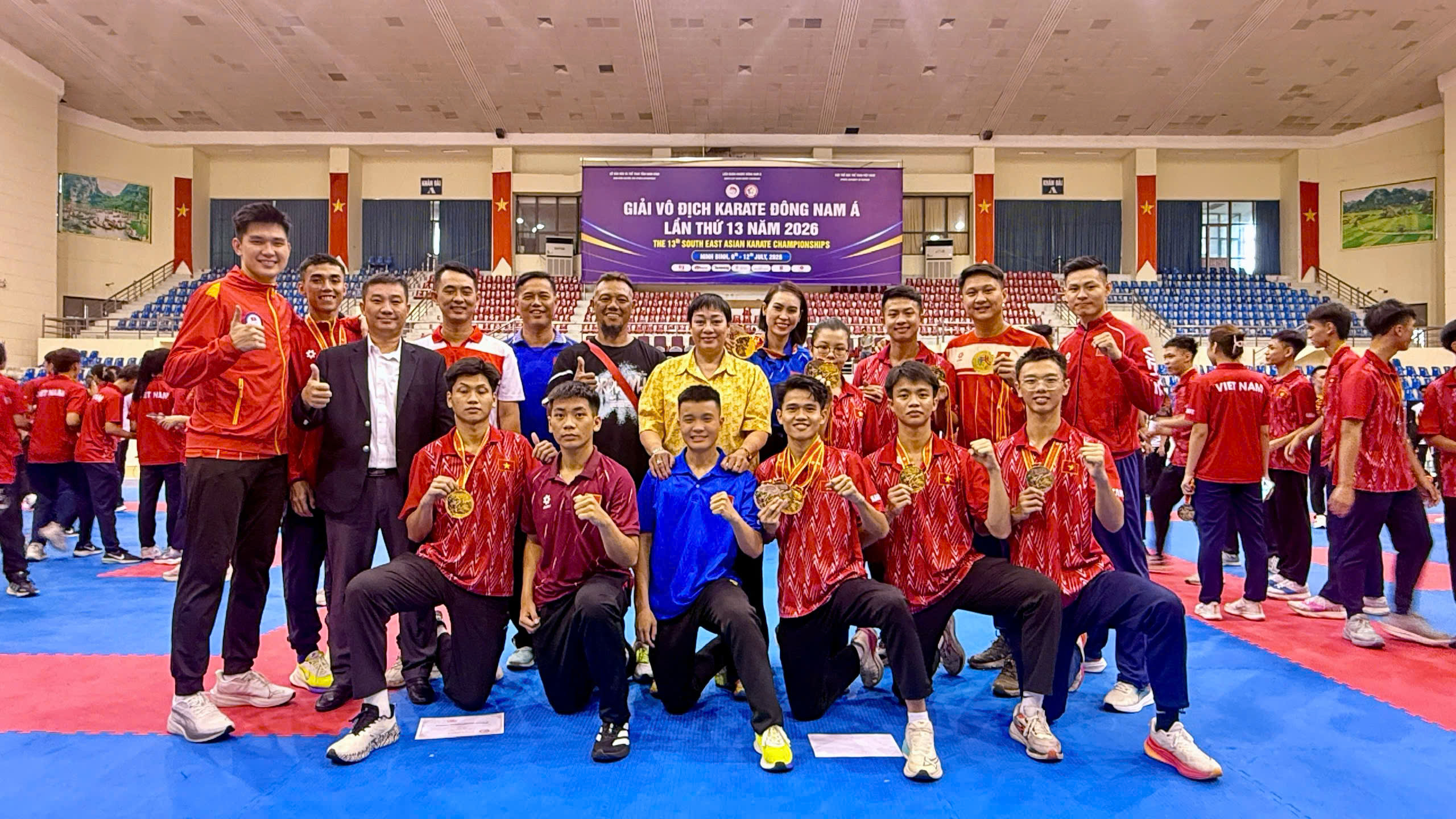 Bà Huỳnh Thị Ngọc Phượng mặc áo vàng ở hàng sau, đứng cùng huấn luyện viên và vận động viên trên thảm đấu tại Giải vô địch Karate Đông Nam Á lần thứ 13 năm 2026.