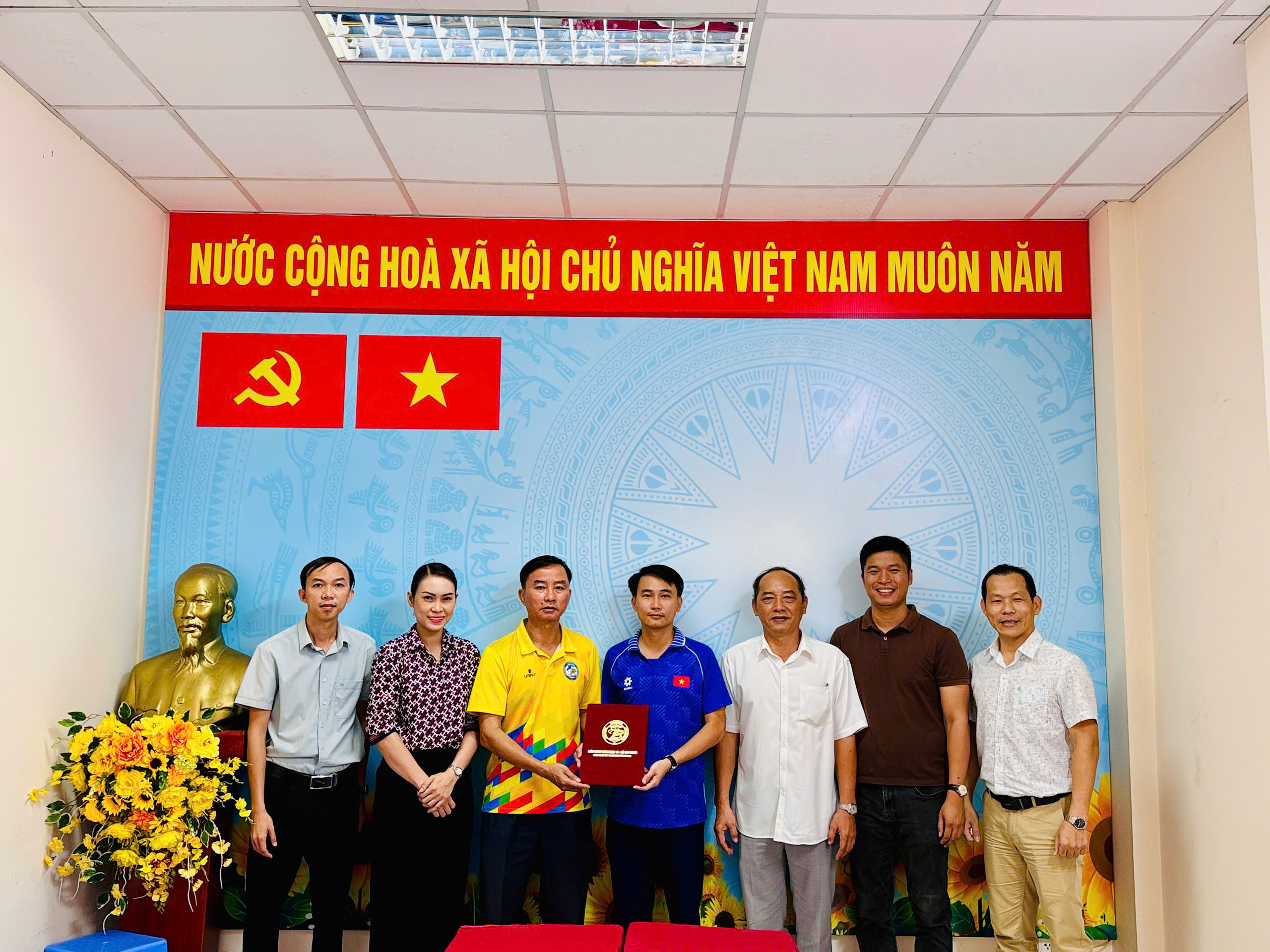 Các thành viên Ban Phát triển phong trào chụp ảnh tại Hội nghị; hai người ở giữa cầm bìa hồ sơ màu đỏ của HKF.