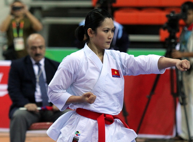 Nguyễn Hoàng Ngân mặc võ phục Karate trắng, đeo đai đỏ và thực hiện một kỹ thuật Kata trong thi đấu.